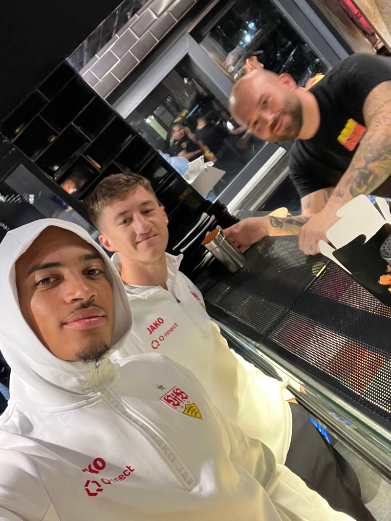 Jamie Leweling (vorne) und Angelo Stiller (hinten) im VfB-Trainingsanzug an der BAM BAM Theke